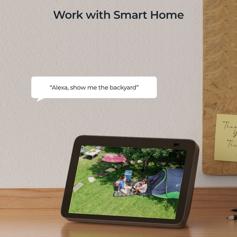 Tablet device showing a couple sitting on a picnic mat on grass in a garden and a speech bubble saying “Alexa, show me the backyard” illustrating the Reolink Argus PT security camera’s smart home compatibility